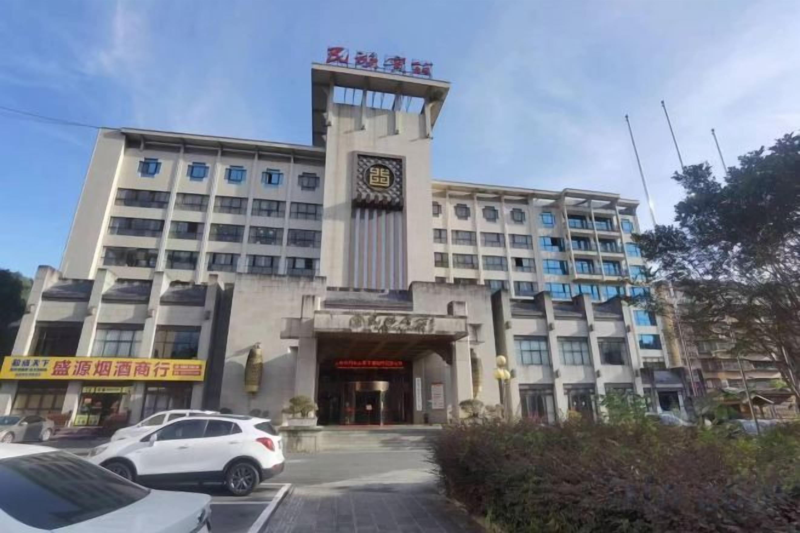 Un hotel de varios pisos con una entrada destacada, una torre del reloj y un cartel.