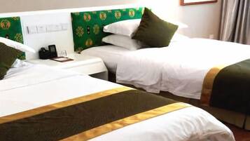 Dos camas individuales con sábanas blancas y cabeceros verdes, una mesita de noche con teléfono, y una ventana con cortinas.