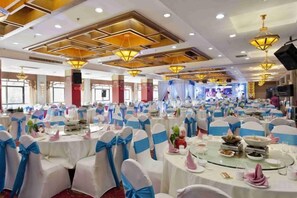 A banquet hall with round tables, chairs, and blue sashes. - Xiangxi National Hotel (Xiangxi)