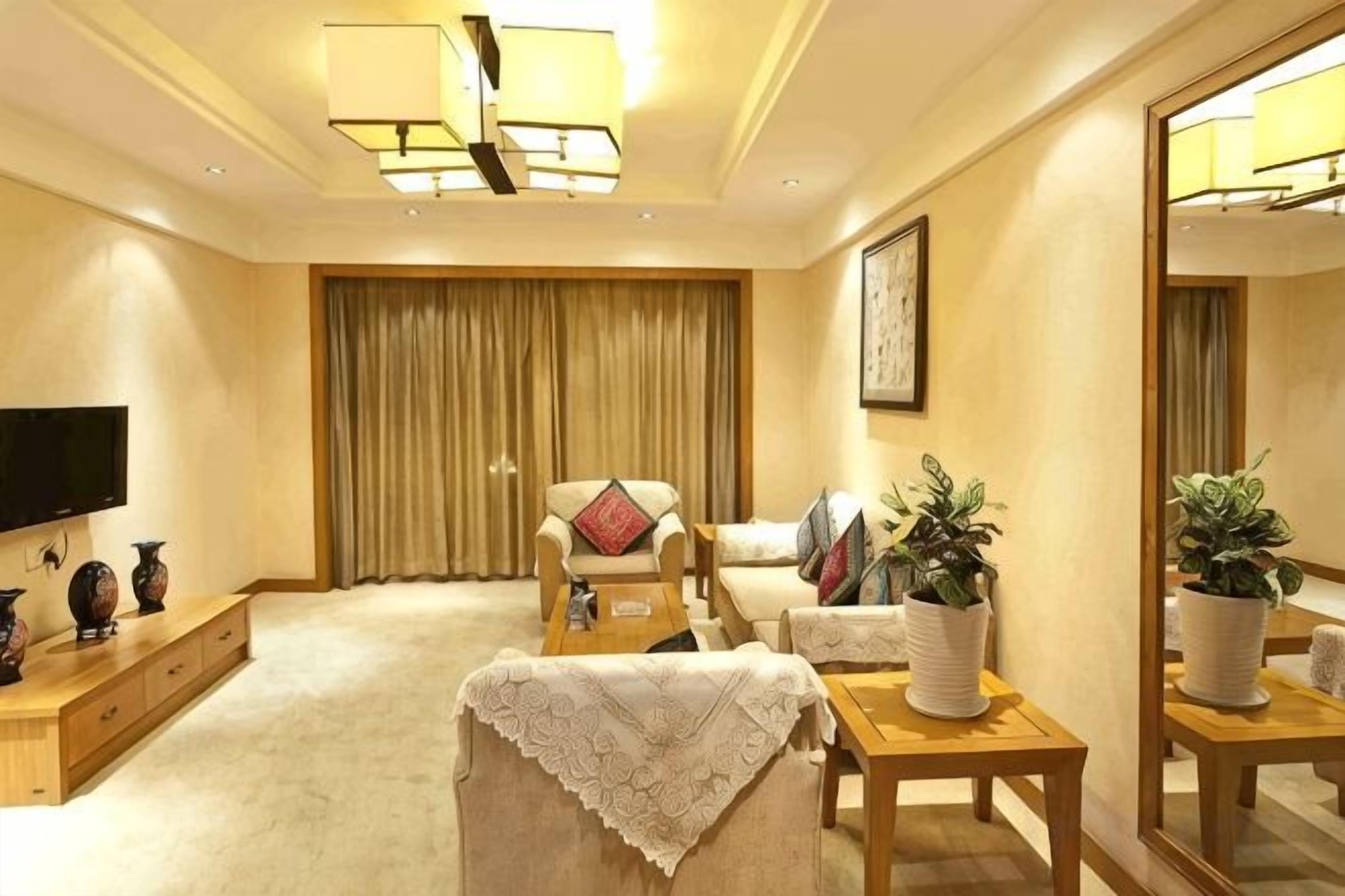 Una sala de estar con una televisión de pantalla plana, un sofá, una silla, una mesa de centro y una planta en maceta.