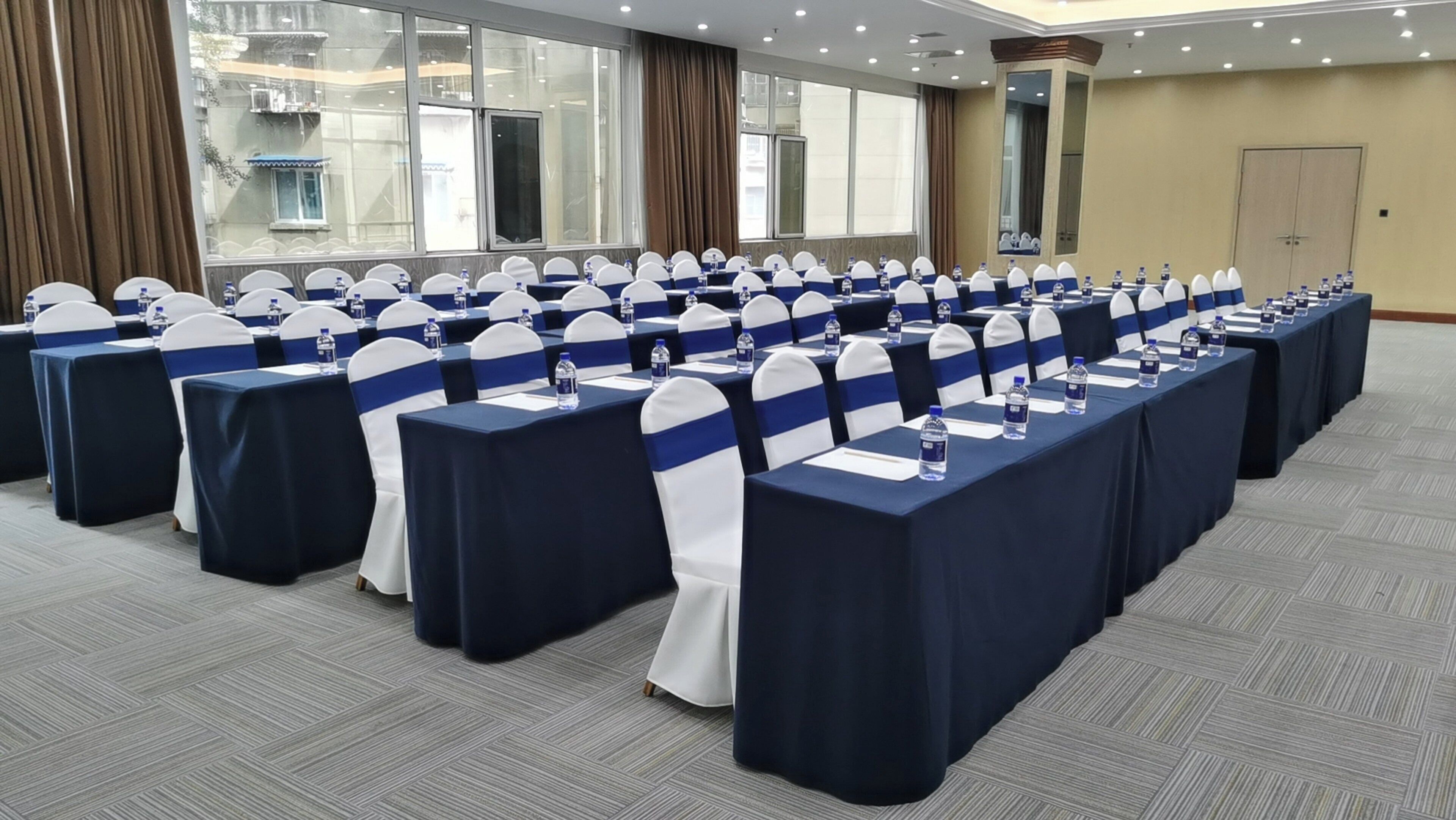 A conference room with rows of tables, chairs, and water bottles.