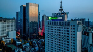 Ein Hochhaus mit Holiday Inn Express-Schild, umgeben von weiteren hohen Gebäuden und einem Baukran im Hintergrund.