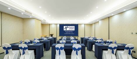 A conference room with tables and chairs, a projection screen, and a carpeted floor.