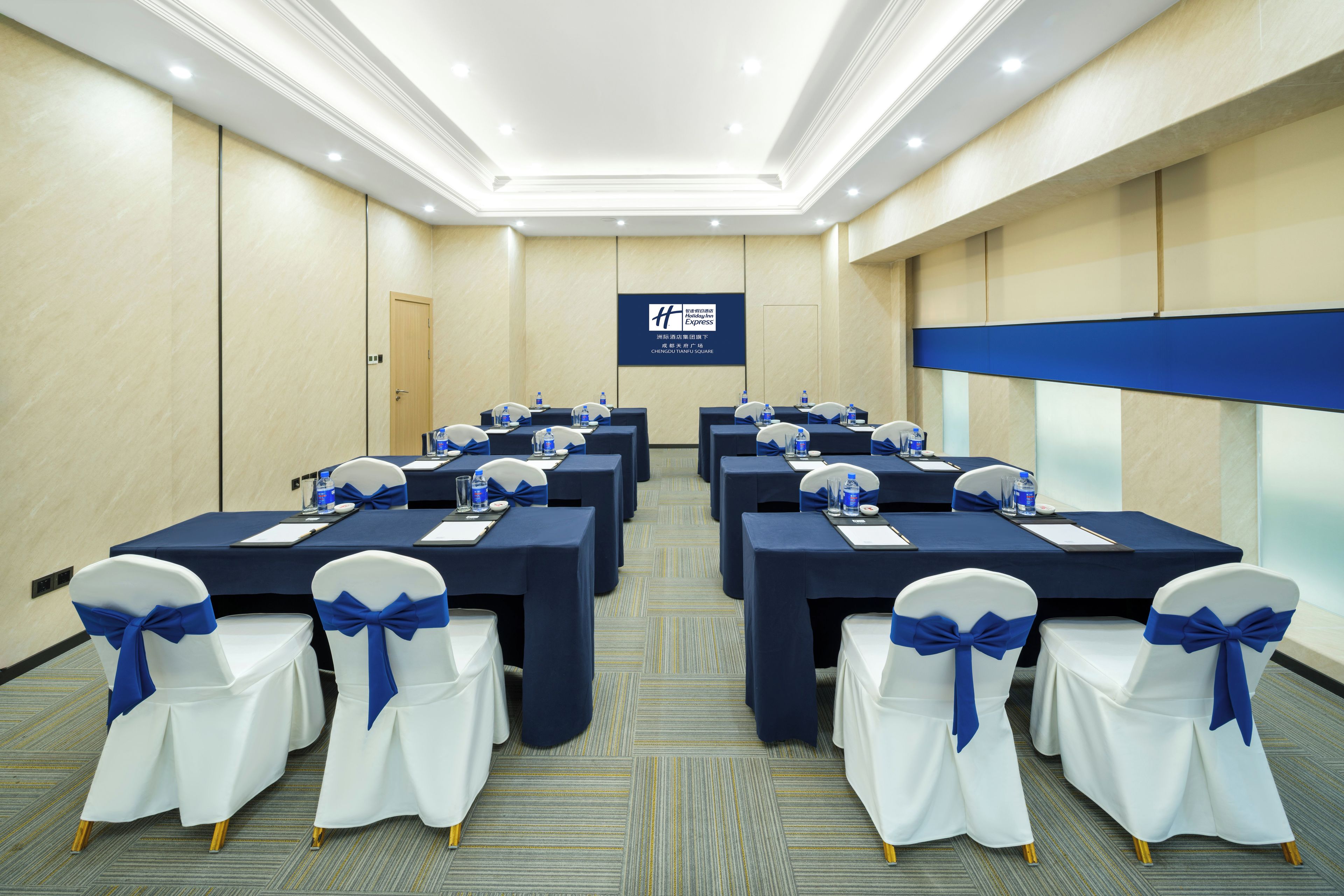 A conference room with multiple tables, chairs, and a projection screen.