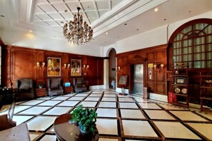 A spacious lobby with a checkered floor, wooden paneling, a chandelier, and seating areas. - Sana Holiday Hotel (Chengdu)