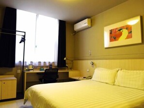 Ein Hotelzimmer mit Bett, Schreibtisch, Stuhl und Klimaanlage.