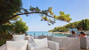 Outdoor wicker furniture with cushions, overlooking a body of water and a beach. - Villa Galijot Plava Laguna (Porec)