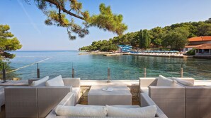 A coastal hotel with outdoor seating by the water, a view of the sea, and a dock area. - Villa Galijot Plava Laguna (Porec)