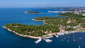 An aerial view of a coastal area with a marina, boats, and buildings. - Villa Galijot Plava Laguna (Porec)