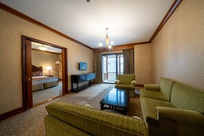 A hotel room with a living area featuring a sofa, a coffee table, a TV, and a large window with curtains. - Duja Chalet Ski Center (Sarikamis)
