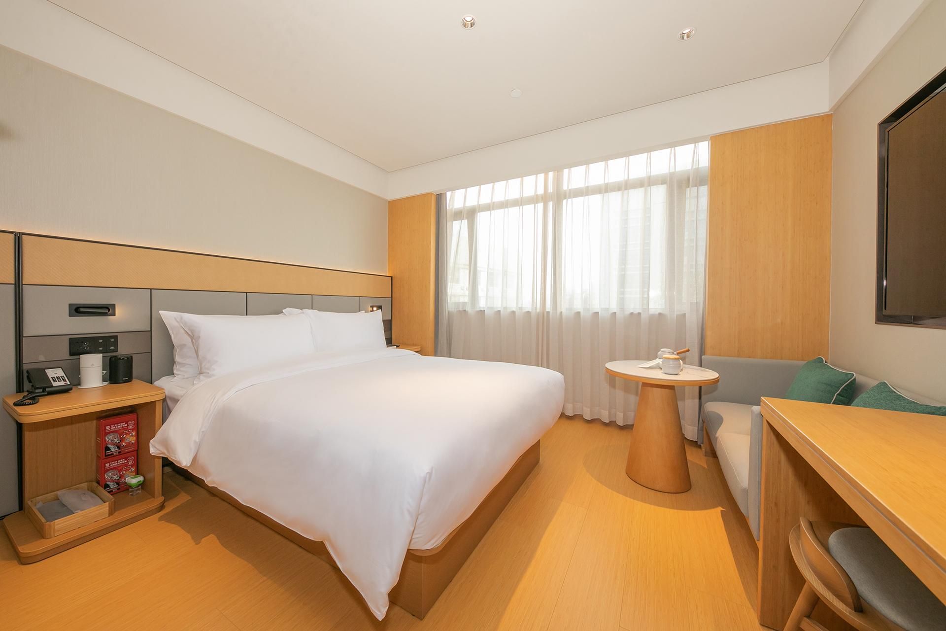 Una habitación de hotel con cama, mesita de noche y un pequeño escritorio con silla.