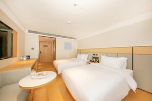 Een hotelkamer met twee bedden, een nachtkastje, een klein rond tafeltje en een spiegel.