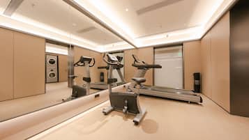 A modern gym with exercise equipment, a large mirror, and a wall-mounted washing machine.
