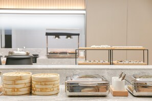 Un espace buffet avec différents récipients contenant de la nourriture et, au fond, un coin salon.