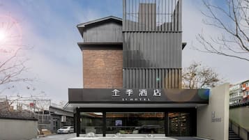 A modern hotel with a prominent entrance, a brick facade, and a clear sky.