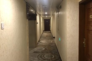 Un couloir d’hôtel avec des revêtements de sol, des portes et des luminaires.