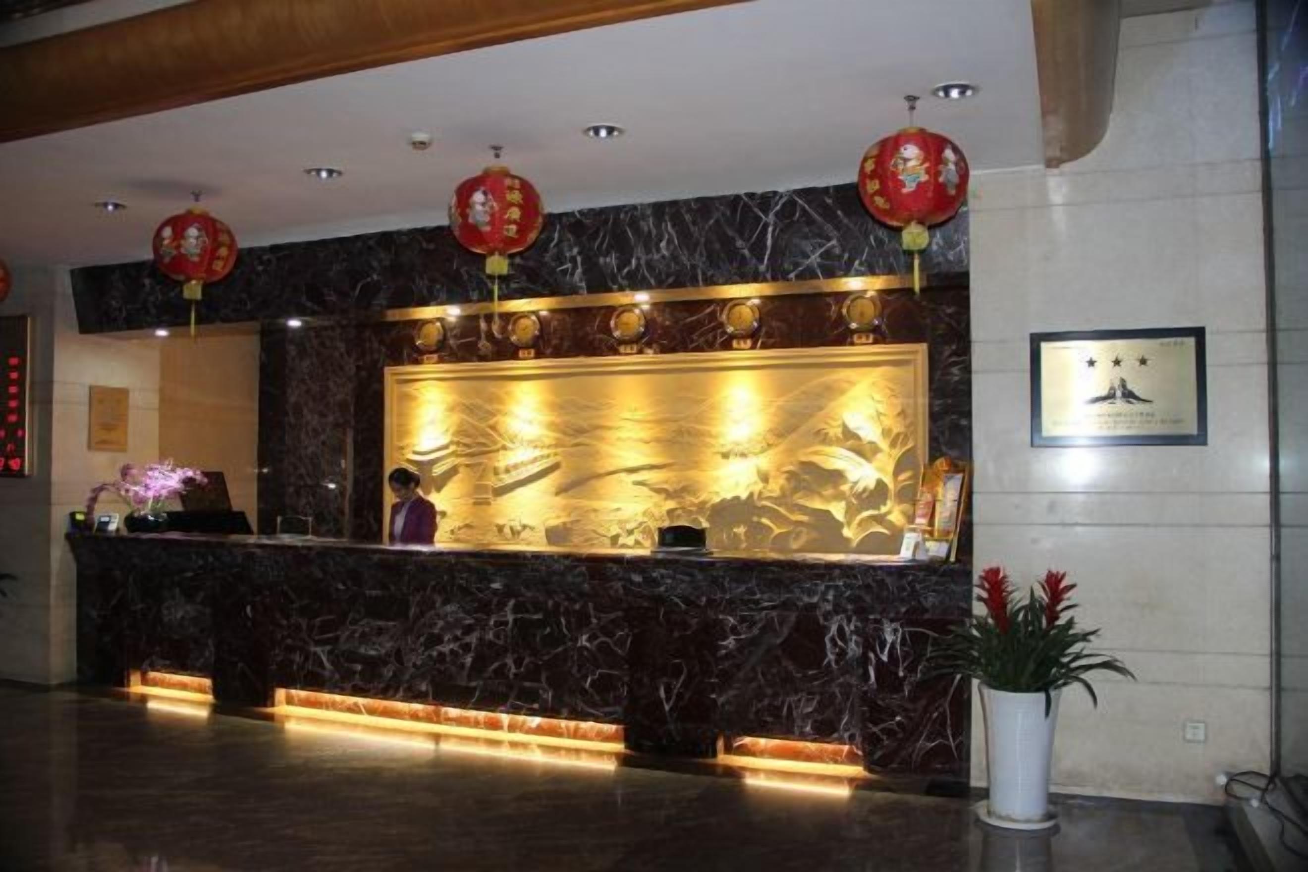 A reception desk with a marble counter, red lanterns, and a framed certificate on the wall.