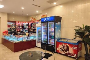 Un espacio con máquinas expendedoras que ofrecen diferentes alimentos y bebidas, un área de descanso y un refrigerador.