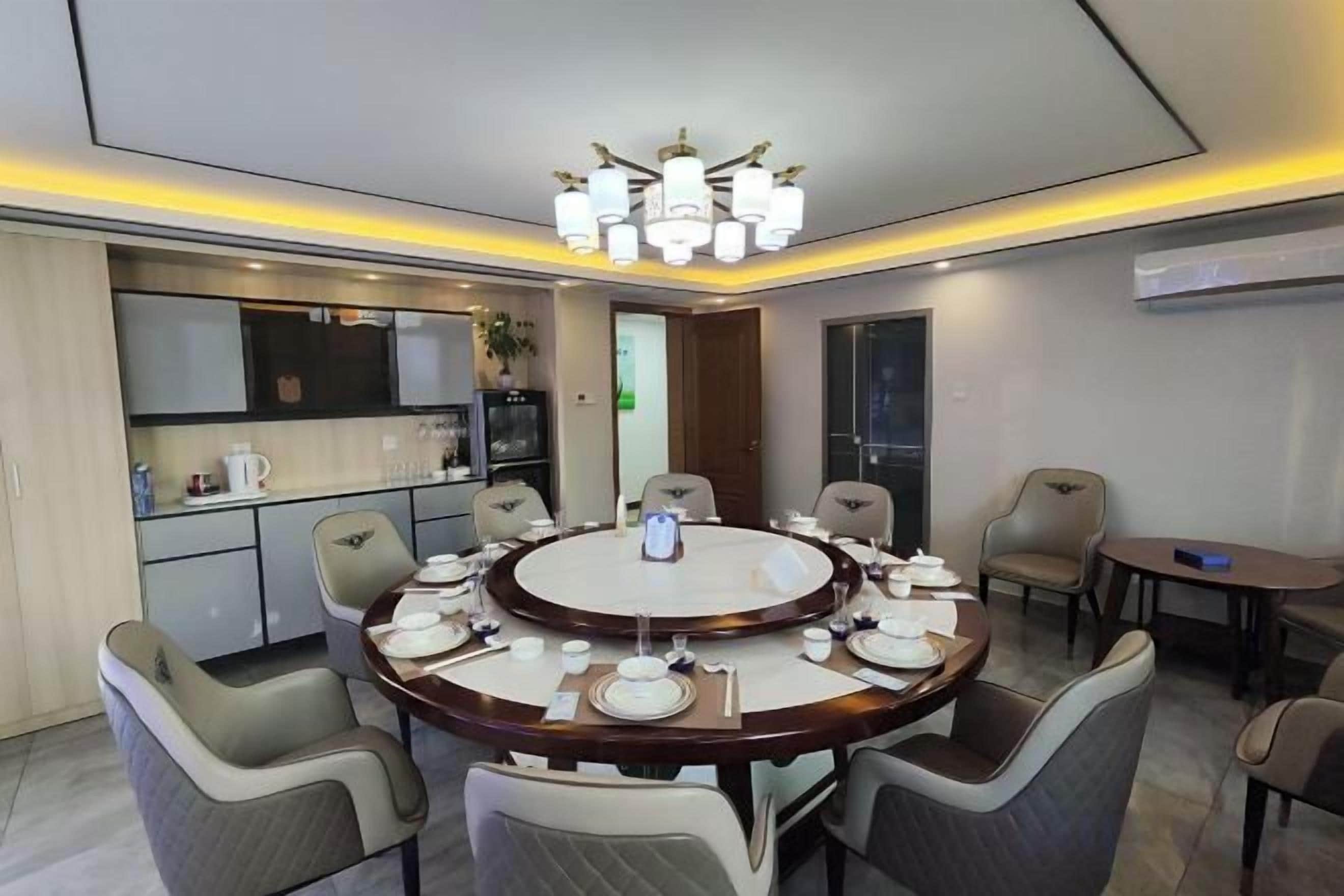 A modern dining area with a round table, chairs, and a chandelier.
