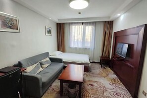 A hotel room with a sofa, a bed, a TV, a desk, and a window with curtains. - Beijing Jinghua Hotel (Beijing)