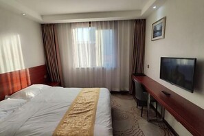 A hotel room with a bed, a TV, a desk, and a window with curtains. - Beijing Jinghua Hotel (Beijing)