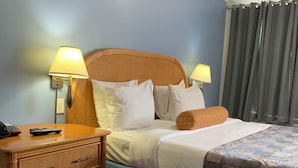 Habitación de hotel con una cama, dos lámparas de noche, una mesita de noche de madera y un teléfono.