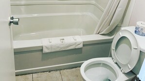 Un baño con bañera, inodoro y cortina de ducha.