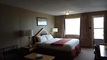 Quarto de hotel com cama, mesas de cabeceira, escrivaninha e uma cadeira.