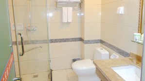 Un baño con ducha envuelta en vidrio, inodoro y lavamanos con encimera de mármol.