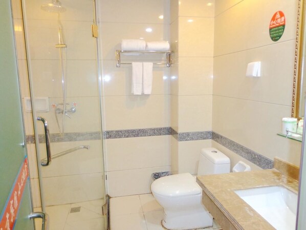 Une salle de bain avec une douche à parois de verre, des toilettes et un lavabo doté d’un plan de travail en marbre.