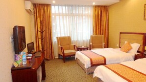 Habitación de hotel con dos camas, un escritorio con televisor, una silla y una ventana con cortinas.