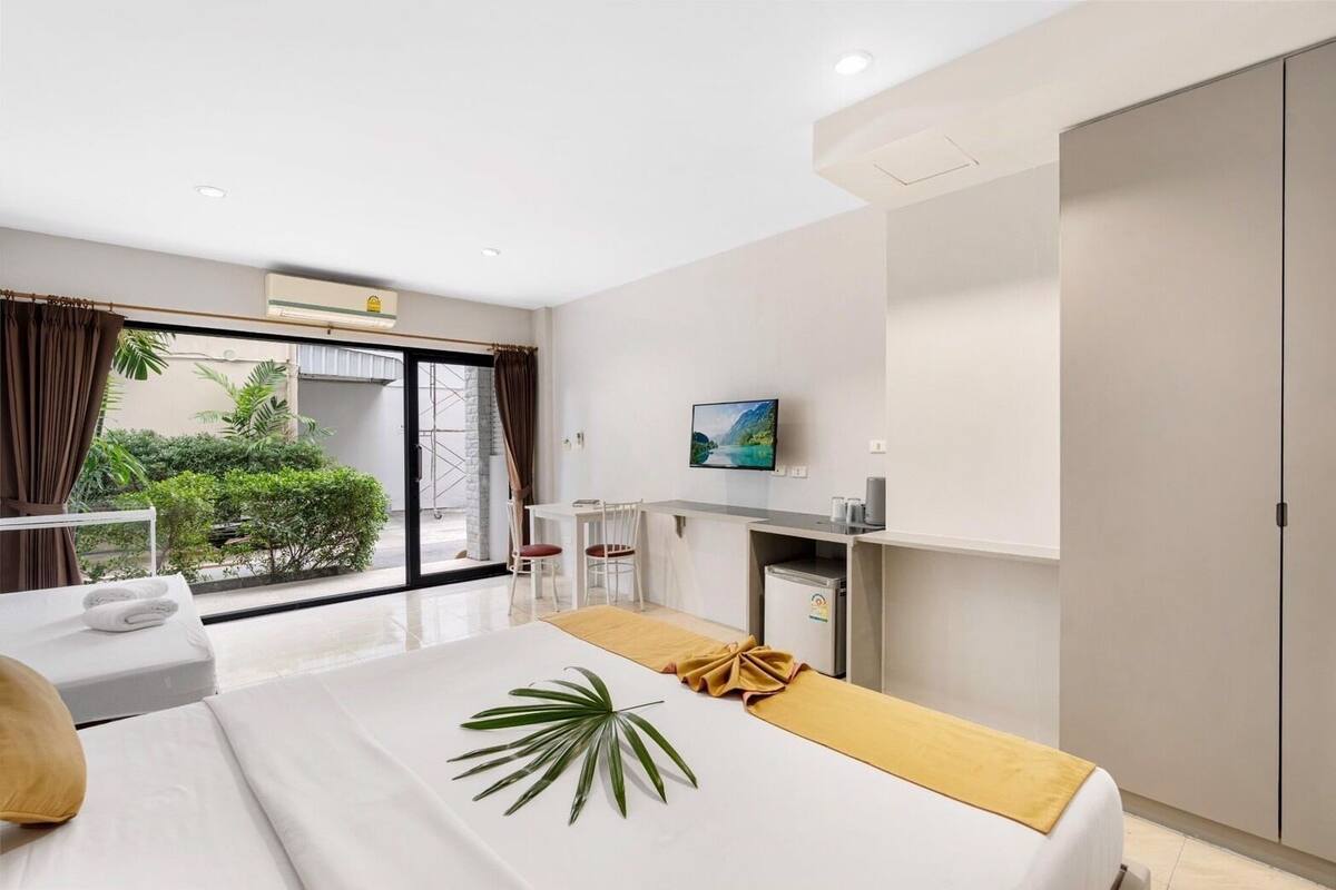 A hotel room with a bed, a desk, a TV, and a wardrobe.