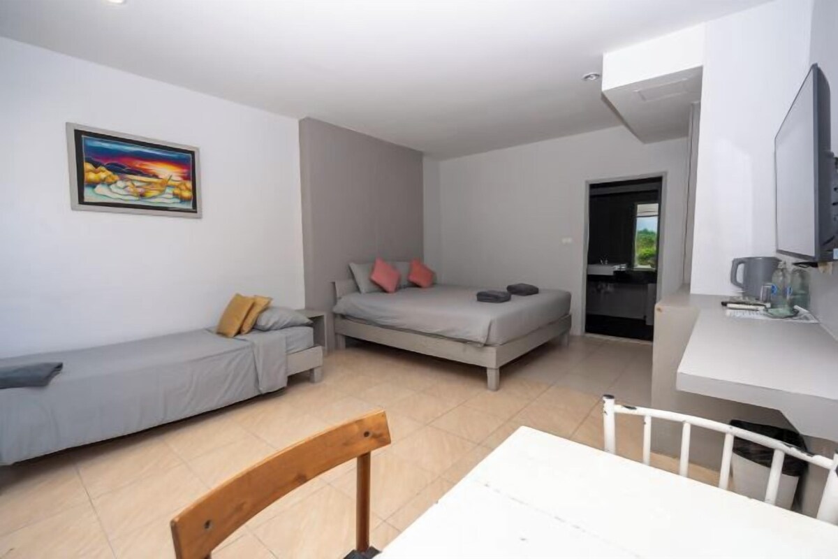 Una habitación compacta con cama, sofá, mesa de comedor y televisor.