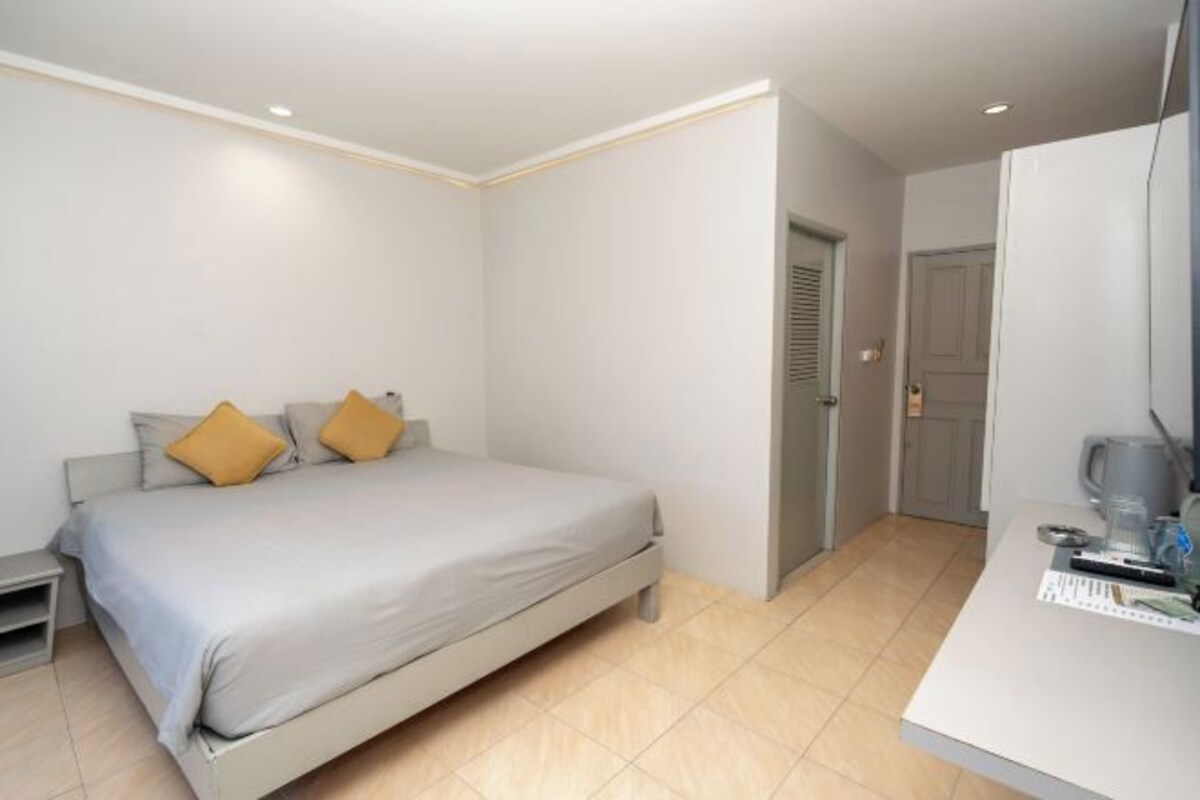 Un dormitorio moderno con cama, mesita de noche y un pequeño escritorio con silla.