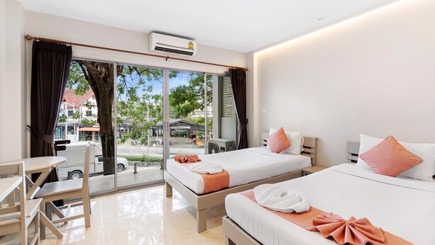 A hotel room with two beds, a desk, and a view of the street. - Chaweng terrace (Koh Samui)