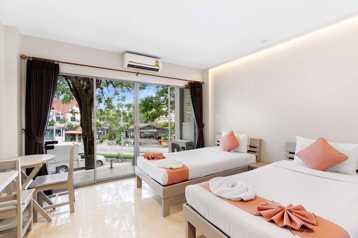 A hotel room with two beds, a desk, and a view of the street.
