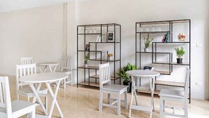 A modern dining area with white furniture and black metal shelving units. - Chaweng terrace (Koh Samui)