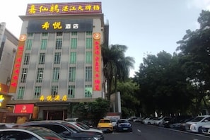 A hotel building with multiple floors, a parking lot in front, and a signboard above the entrance. - Xi Yue Hotel（Guangzhou Changlong Nancun area） (Guangzhou)