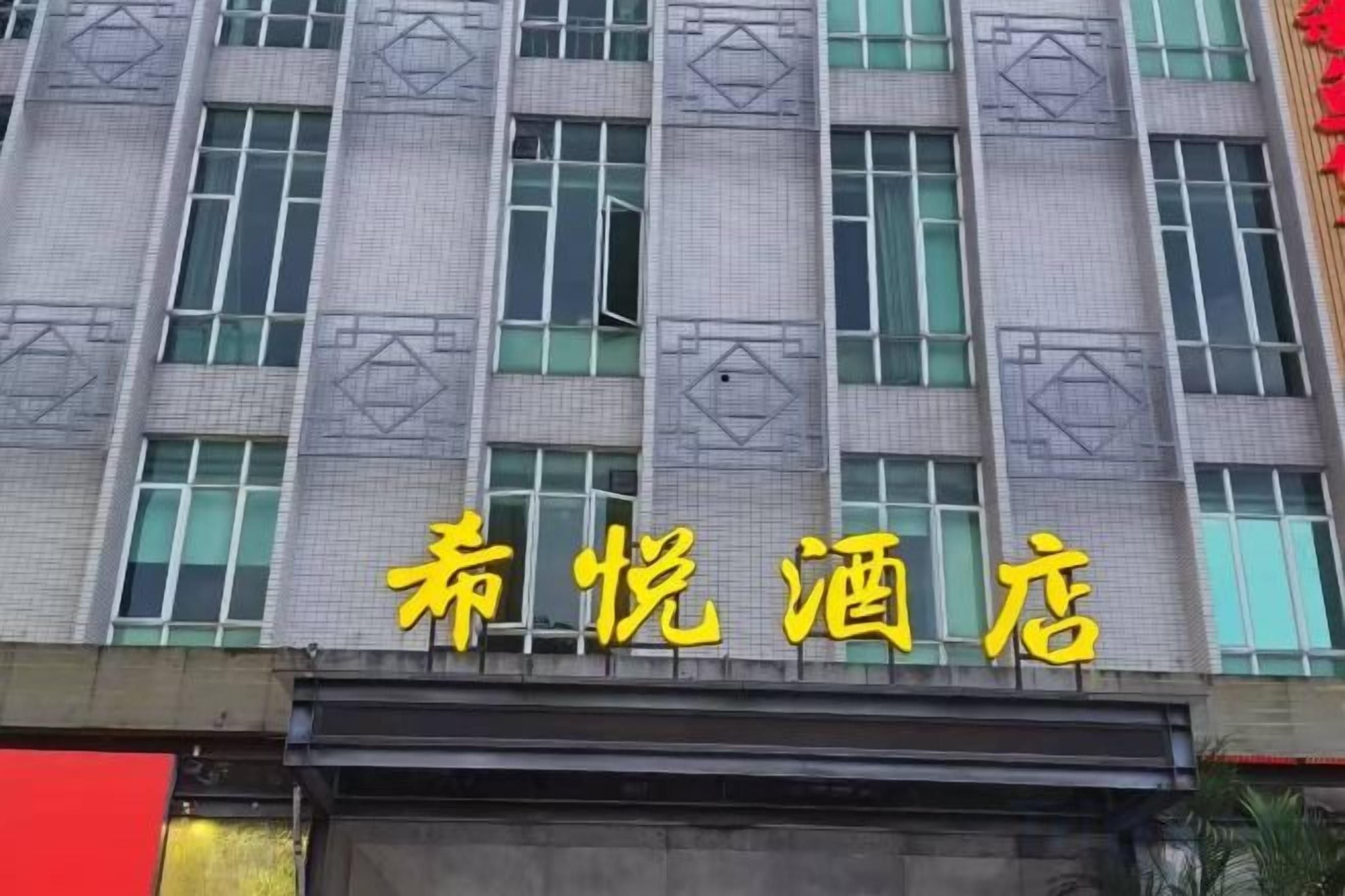 A building with a sign that reads '喜悦酒店' (Xihui Hotel).