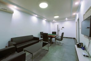 A room with a sofa, chairs, a table, a TV, and a door. - Xi Yue Hotel（Guangzhou Changlong Nancun area） (Guangzhou)