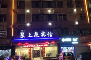 A hotel with a prominent sign, multiple floors, and a parking area in front. - Hotspring Quanshangquan Hotel (Xianning)