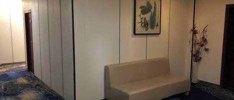 Una habitación con un banco, una obra de arte enmarcada en la pared y una alfombra estampada.