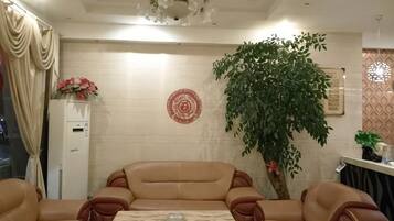 Una habitación con un conjunto de sofá, una mesa de centro, un plato decorativo en la pared y una planta en maceta.