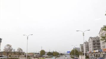 A wide urban road with multiple lanes, streetlights, and buildings on both sides.