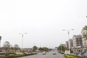 A wide urban road with multiple lanes, streetlights, and buildings on both sides.