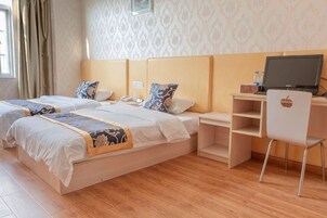 Una habitación de hotel con dos camas, un escritorio con computadora y una silla.