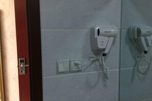 A hairdryer mounted on a wall with a power outlet and a cord. - Xingainian Business Hotel (Zhenjiang)