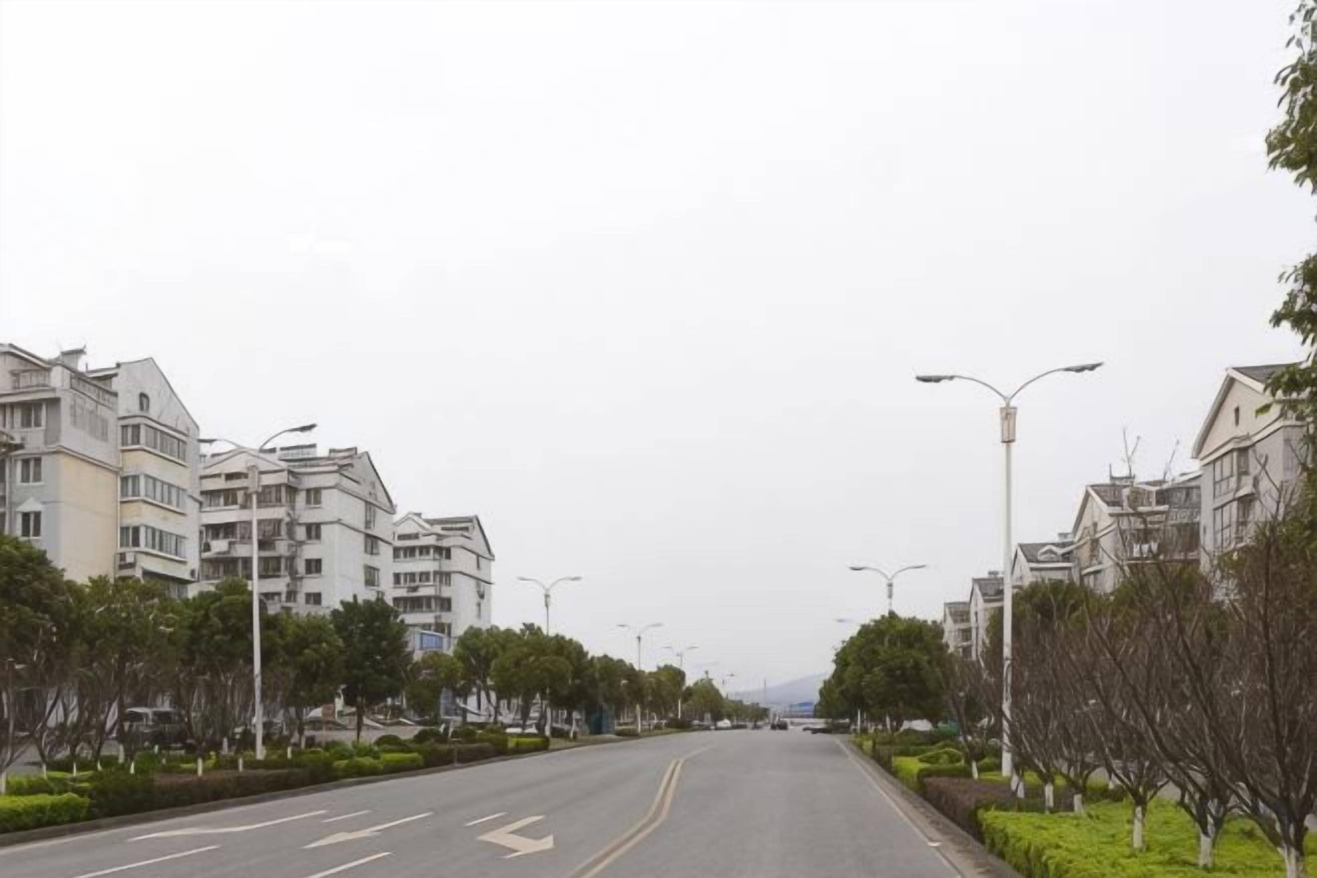 Una calle residencial flanqueada por modernos edificios de apartamentos, farolas y árboles.