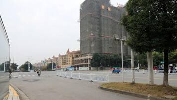 Una calle con un edificio en construcción, una acera y un árbol.