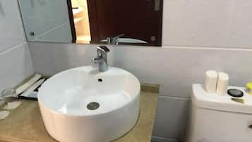 A bathroom with a white sink, a mirror, and a toilet.